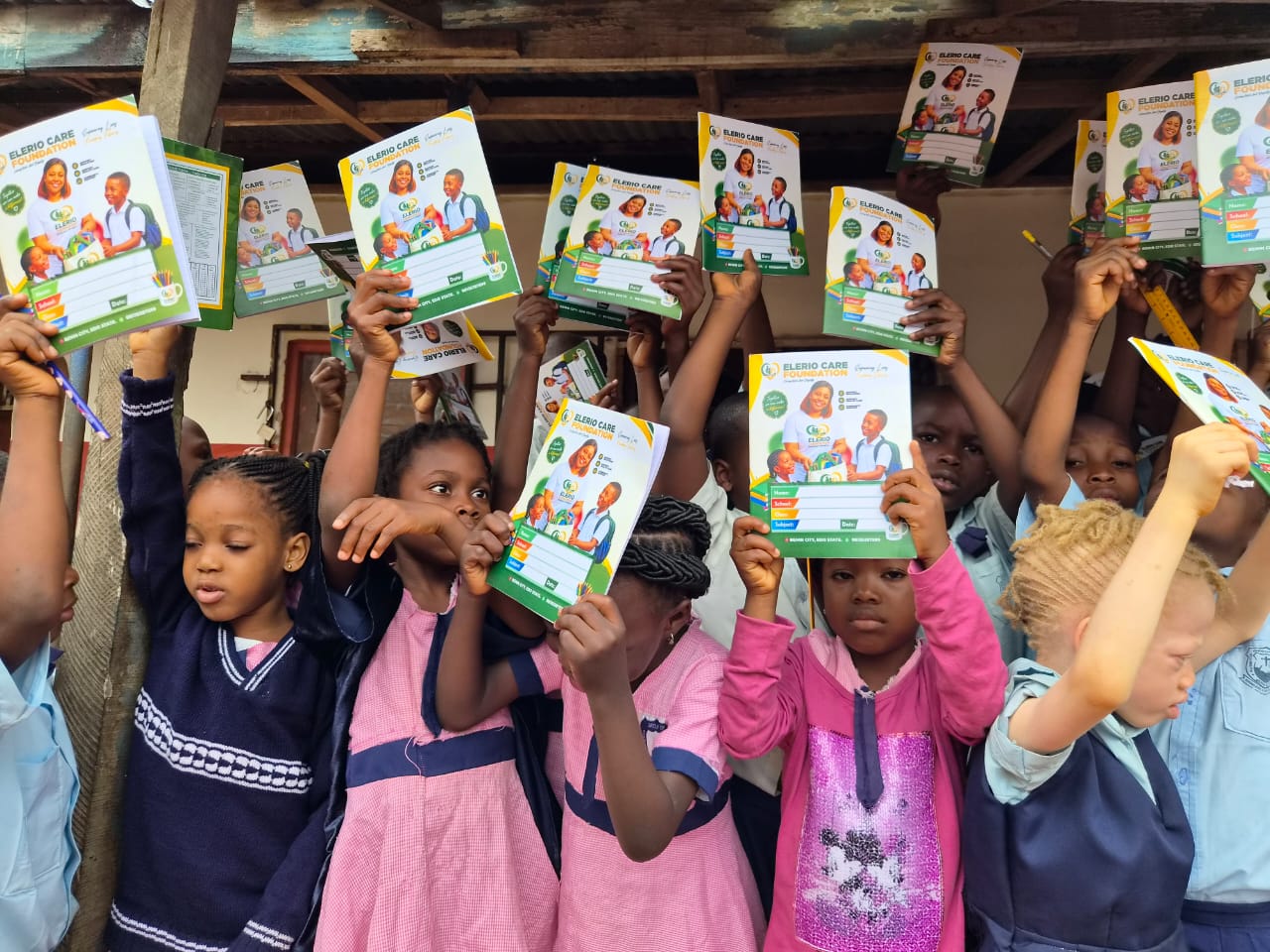 Schoolchildren holding their new learning materials overhead